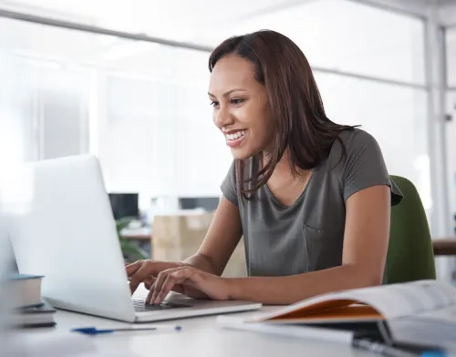 Woman smiling and working on her laptop