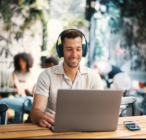 Middle aged man wearing headphones and working at his laptop