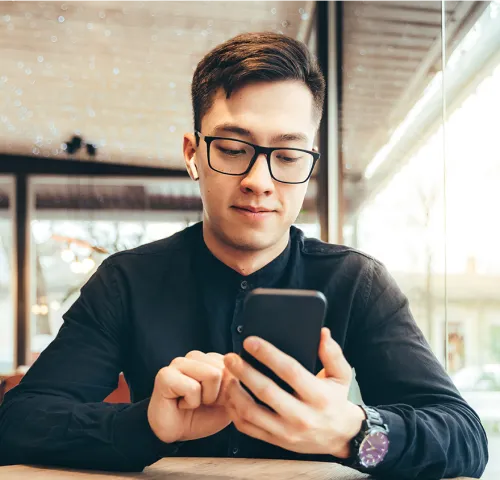 Young male professional with glasses looking at his phone