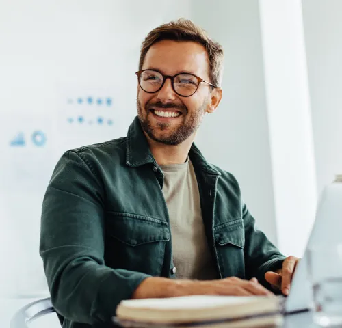Middle aged man with glasses smiling while working at his desk