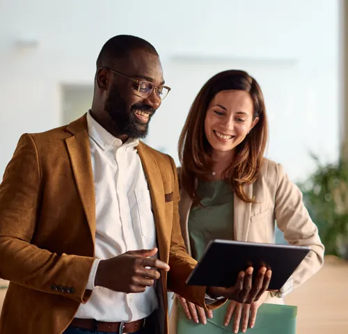 Coworkers looking at a tablet while smiling