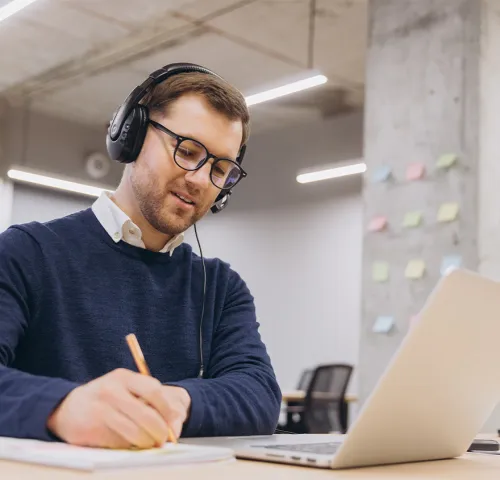 Young male professional studying at his desk with headphones on