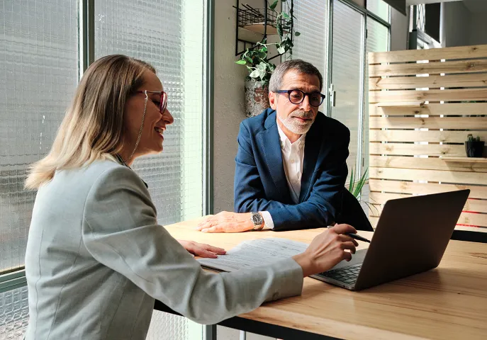 Two senior professionals looking at a laptop screen together
