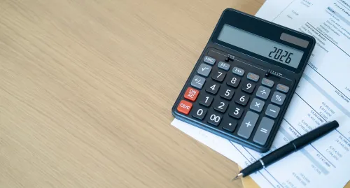 Calculator on the table with a pen and paper